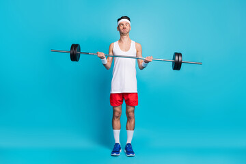 Full size photo of funky man lift heavy dumbbell weight make funny face isolated on blue color background