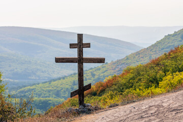 Orthodox Christian Bow Cross monument on slope of Mangup-Kale which is ancient cave town in Crimea. Scenic landscape.
