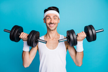Photo of young sportsman happy positive smile bodybuilding arms dumbells isolated over blue color...