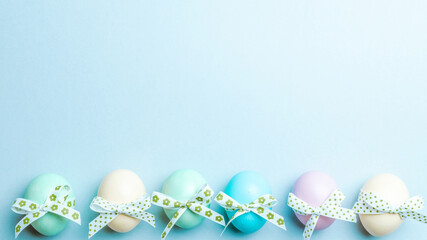 Easter flat. Colorful egg with tape ribbon on pastel blue background in Happy Easter decoration. Spring holiday top view concept.