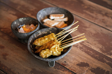 serve curry pork grill with wood stick on coconut dish serve on wood table