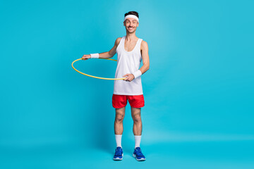 Photo of young excited man happy smile spin plastic circle around waist isolated over blue color background