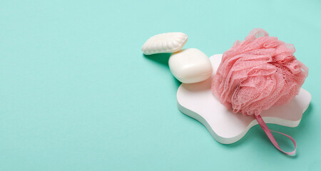 Closeup of aromatic white bar of soap, pink fluffy shower sponge on the blue surface.Empty space