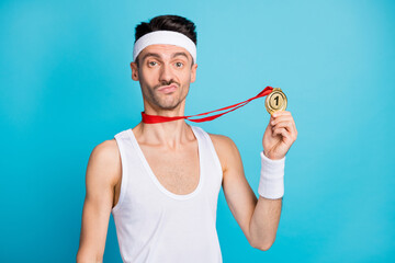 Photo of young sportsman serious hold gold medal win victory competition isolated over blue color background