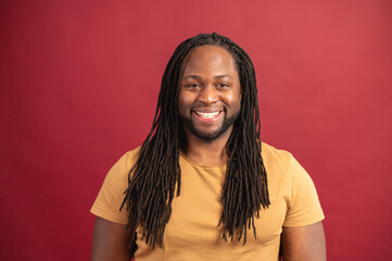 Portrait of smiling young handsome African American guy with dreadlocks in yellow t-shirt standing...