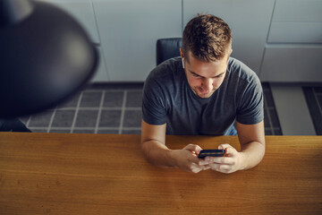 The digital age. A bird's eye view of a young man who sits in blue at the kitchen table and plans...