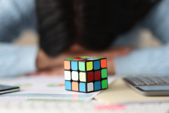 Rubik Cube On Table With Tired Woman In Background. Way Out Of Desperate Situations Concept