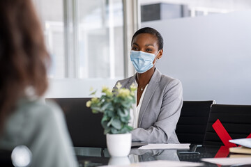 Mature black businesswoman wearing protective face mask in office