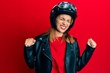 Hispanic young woman wearing motorcycle helmet very happy and excited doing winner gesture with arms raised, smiling and screaming for success. celebration concept.