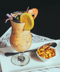 Peruvian traditional food, leche de tigre decorated with shrimp, onion, cilantro, lemon 