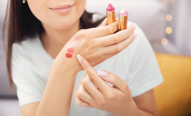 Happy woman beauty blogger is review cosmetics product is choosing new lipstick applies colour on...