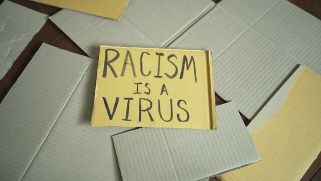 Racism is a virus was written on a cardboard