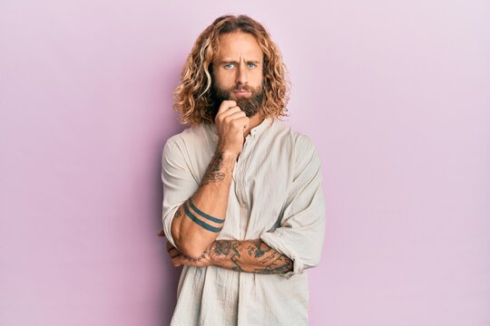 Handsome man with beard and long hair wearing casual clothes thinking concentrated about doubt with finger on chin and looking up wondering