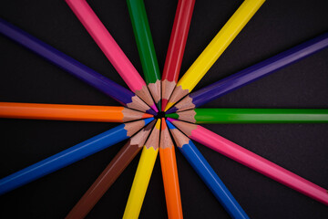 Fototapeta premium Pencils of different colors on a black background. Top view. Bright background from pencils. 