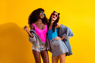 Low angle view photo of two attractive young girl happy positive smile have fun wear sunglass...