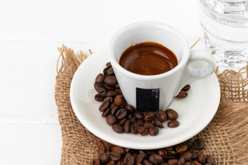 Cup of espresso with glass of water on white table