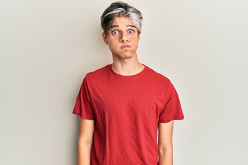 Young hispanic man wearing casual clothes puffing cheeks with funny face. mouth inflated with air, crazy expression.