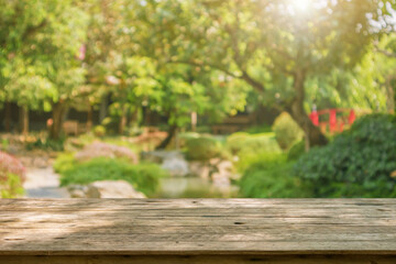 Empty wood table top with abstract blur park garden pond background