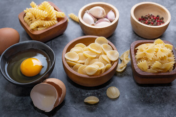 Mixed dried pasta selection on wooden background. composition of healthy food ingredients isolated on black stone background, top view, Flat lay.