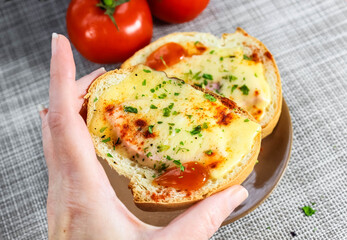 In the woman is hand is a sandwich with melted cheese.