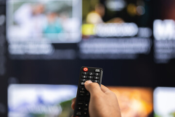 Close up male hand holding remote control pointing to change the programme television.