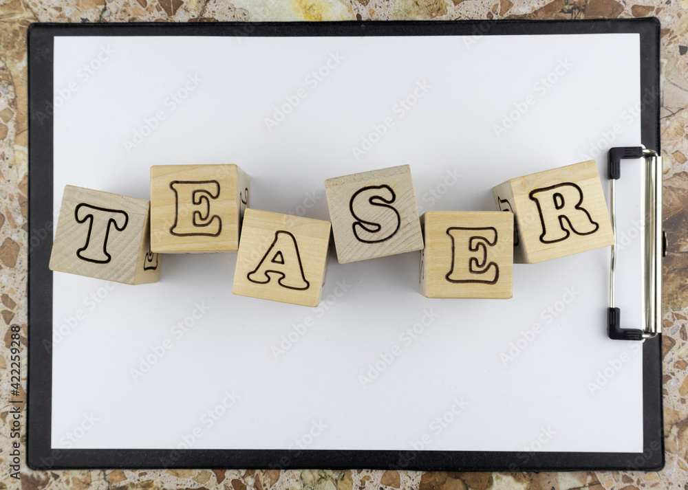 Poster teaser concept with wooden blocks with alphabet letters arranged on a blank sheet of white paper on 
