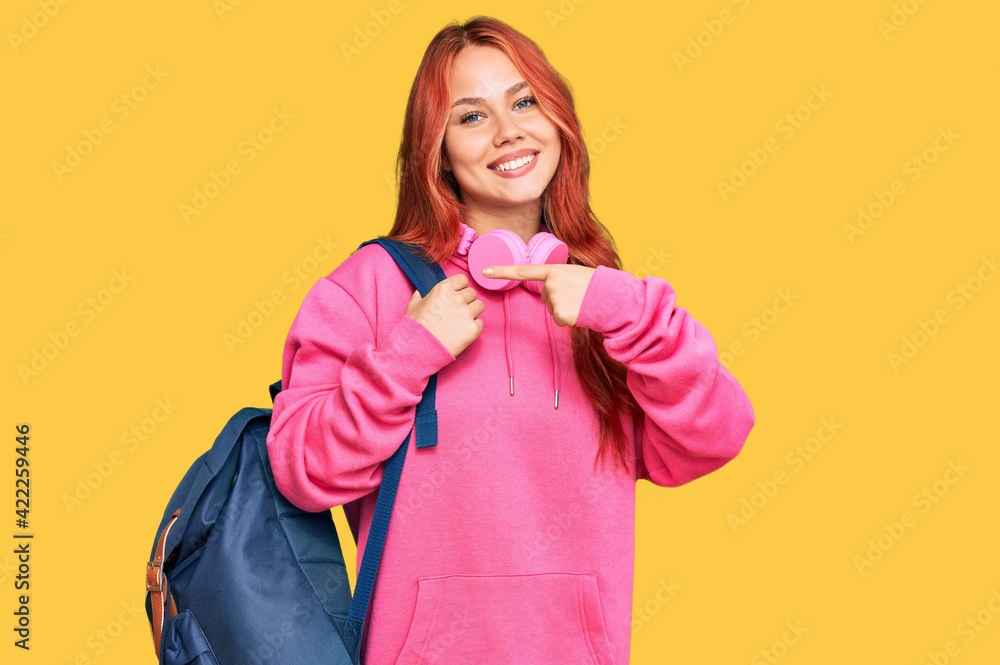 Canvas Prints Young redhead woman holding student backpack and books smiling happy pointing with hand and finger