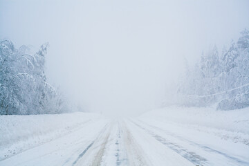 Winter blizzard in the driving north empty road landscape with white trees and snow with fog in the...