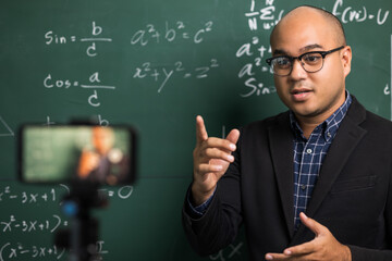 Indian young teacher man teaching online video conference live stream by smartphone. Asian teacher teaching mathematics class webinar online for students learning.