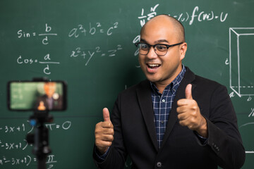 Indian young teacher man teaching online video conference live stream by smartphone. Asian teacher teaching mathematics class webinar online for students learning.