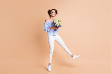 Fototapeta na wymiar Full body photo of young excited girl amazed surprised receive flowers bouquet jump up isolated over beige color background