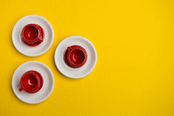 Red cups with the dots on a white plate. Background yellow.