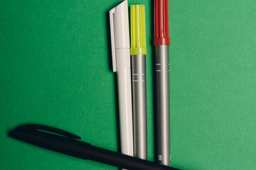 multicolored pens on a green background office supplies work stationery