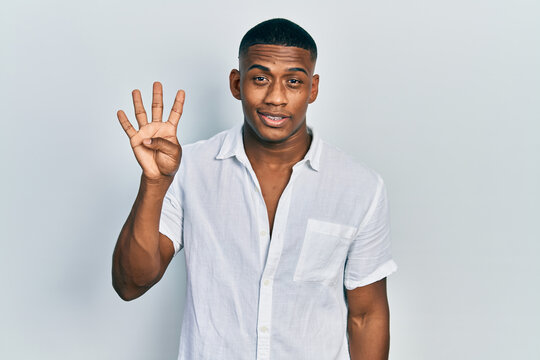 Young black man wearing casual white shirt showing and pointing up with fingers number four while smiling confident and happy.