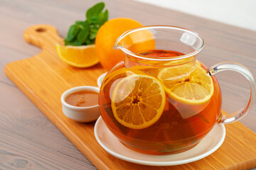 Glass teapot with black tea and pieces of citrus