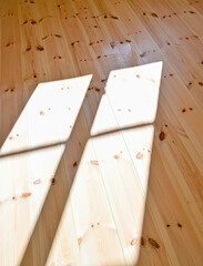 Naklejka na ściany i meble sunshine through window on wooden floor making shadows