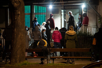 Naklejka na ściany i meble People stand in long queues on cold night in front of the checkpoint as they wait to receive the vaccine against corona virus - covid 19 or do PCR test. Mass vaccination. Belgrade, Serbia 20.03.2021