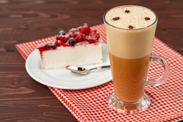 Cup of latte coffee with piece of berry cheesecake