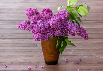  Bouquet purple (Violet) Lilac Flower  in a brown vase a wooden surface. Syringa vulgaris (common lilac). Spring flowers.