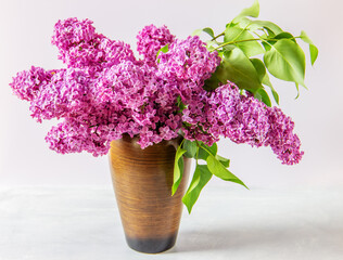 Bouquet purple (Violet) Lilac Flower  in a brown vase on the table. Syringa vulgaris (common lilac). Spring flowers