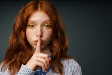 Young ginger white woman showing silence gesture at camera