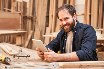 Zufriedener Schreiner Lehrling mit Tablet Computer