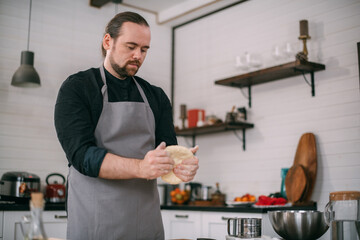 A male chef prepares dough at home in the kitchen