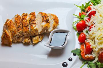 Tagliata di pollo cotto a bassa temperatura con contorno di pomodori, formaggio e rucola