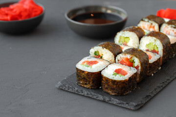 Maki sushi roll served on stone plate on gray background