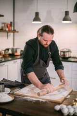 A male chef prepares noodles at home in the kitchen.