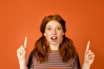 Ginger shocked woman with tails pointing fingers upward