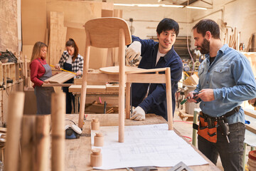 Schreiner als Möbelbauer bauen einen Holz Stuhl