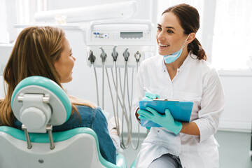 European mid dentist woman smiling while working with patient - obrazy, fototapety, plakaty