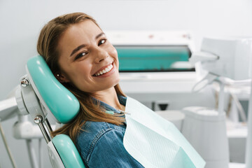 European young woman smiling while sitting in medical chair
